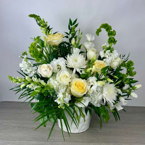 White and pale yellow floral arrangement in a white vase