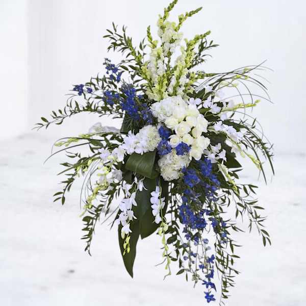 Tall floral spray with white and blue flowers and cascading greenery