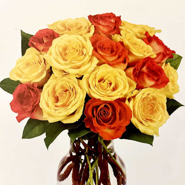 Bouquet of yellow, orange, and red roses in a clear glass vase