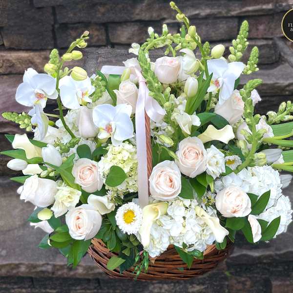 Large basket of white orchids, roses, hydrangeas and calla lilies with soft peach accents.