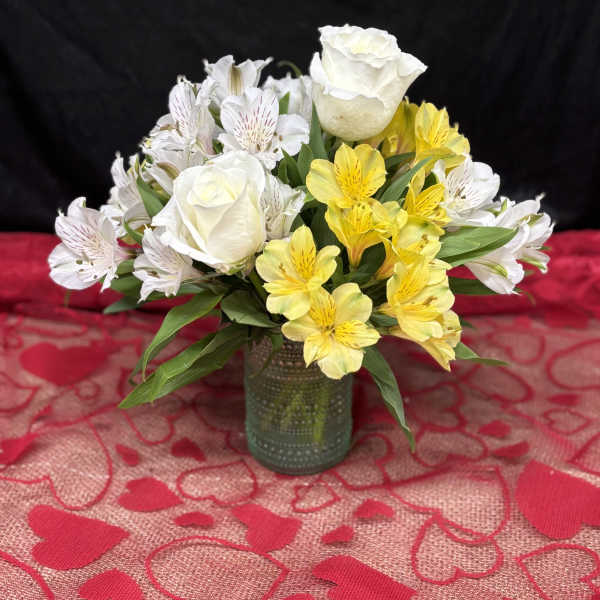 White roses and yellow alstroemeria in a small glass vase