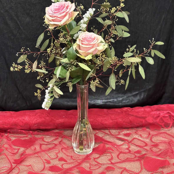 Pink roses in a clear glass vase with airy greenery