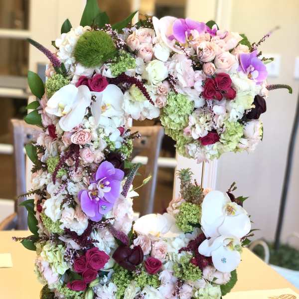Large floral arrangement shaped like the number 5 with pink, white, and purple blooms