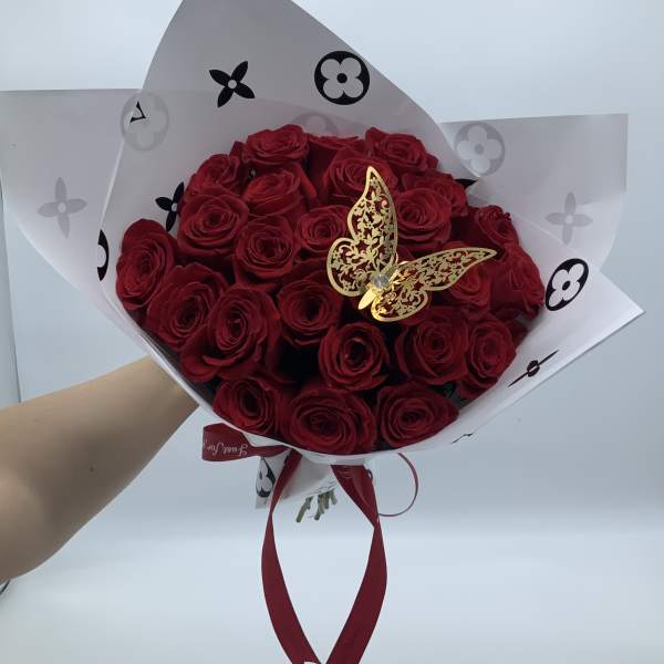 Bouquet of red roses wrapped in white paper with a gold butterfly accent
