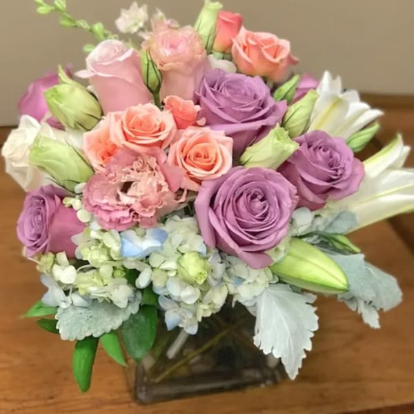 Bouquet of pink and purple roses with white lilies in a glass vase
