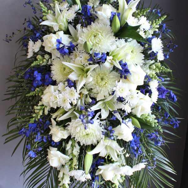 Large white and blue funeral spray on a standing easel