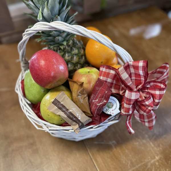 Fruit basket with pineapple, apples, oranges, and wrapped candies