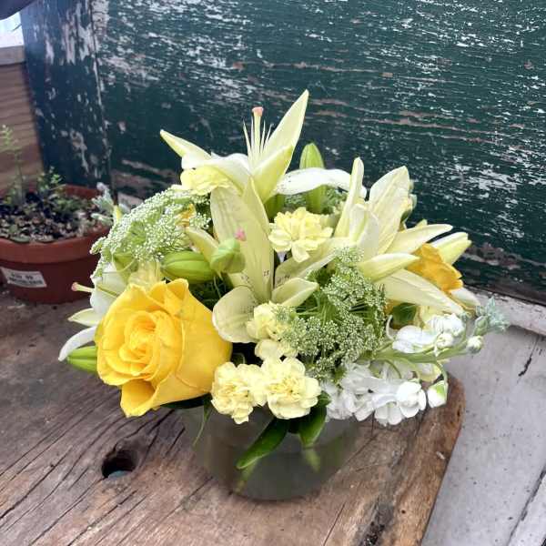 Yellow roses and white lilies arranged in a glass vase