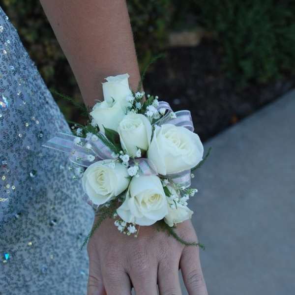 White rose wrist corsage with ribbon on a person's wrist
