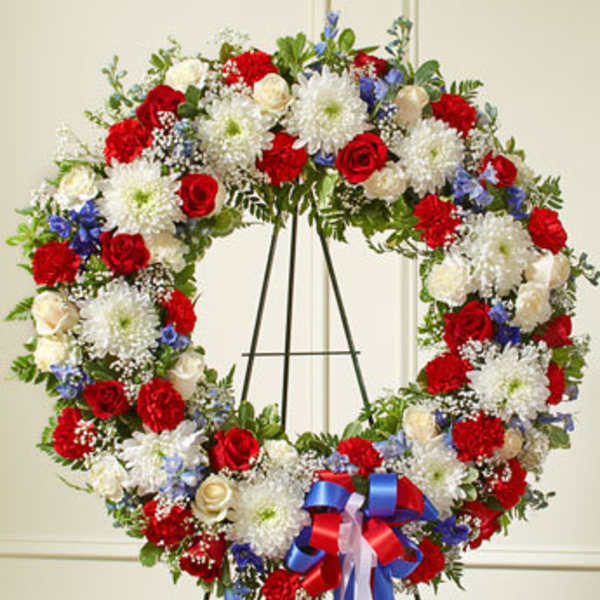 Large red, white, and blue floral wreath on a stand with ribbon
