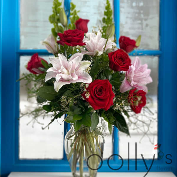 Red roses and pink lilies in a clear glass vase