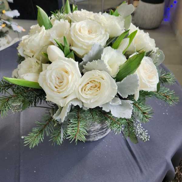 Low arrangement of white roses and tulips with pine branches in a gray pot