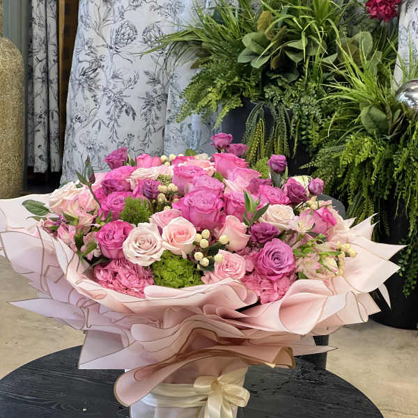 Large pink rose bouquet wrapped in pale pink paper with a ribbon