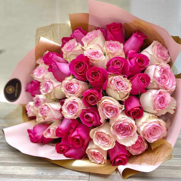 Large bouquet of hot pink and pale pink roses wrapped in pink and kraft paper