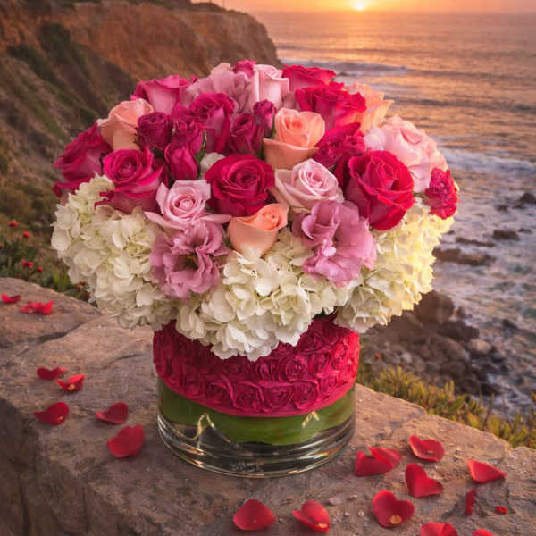 Pink and peach roses arranged with white hydrangeas in a glass vase