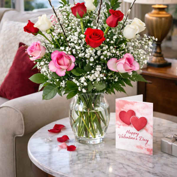 Bouquet of red, pink, and white roses in a glass vase with a Valentine card