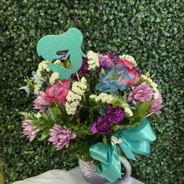 Mixed pink and purple bouquet in a white mug with a teal ribbon