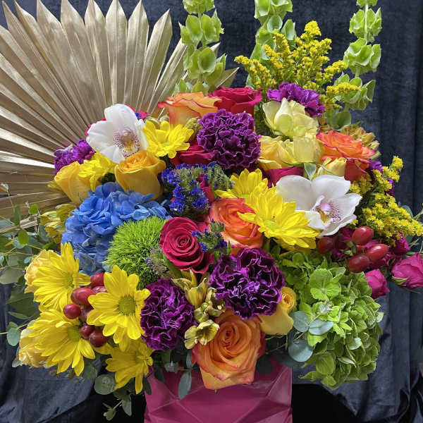 Colorful mixed bouquet in a pink vase with a gold fan backdrop