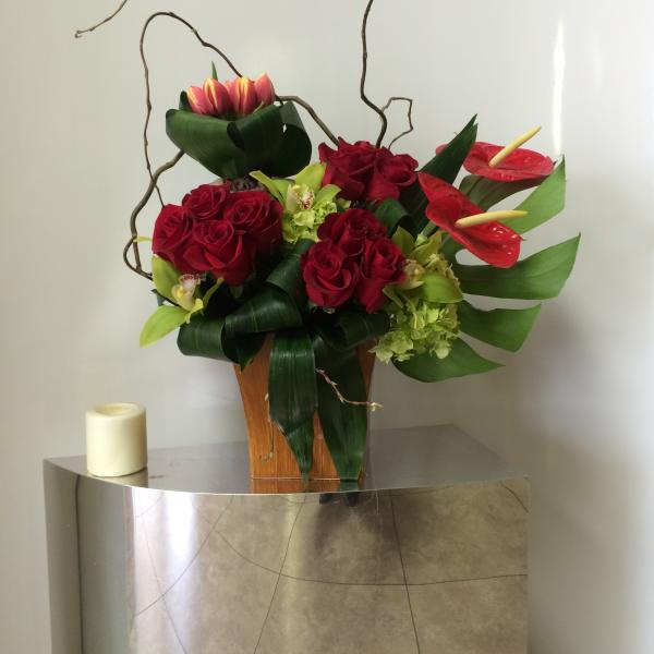 Red roses and red anthuriums arranged in a wooden vase