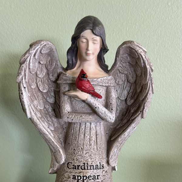 Angel figurine holding a red cardinal with text on the base