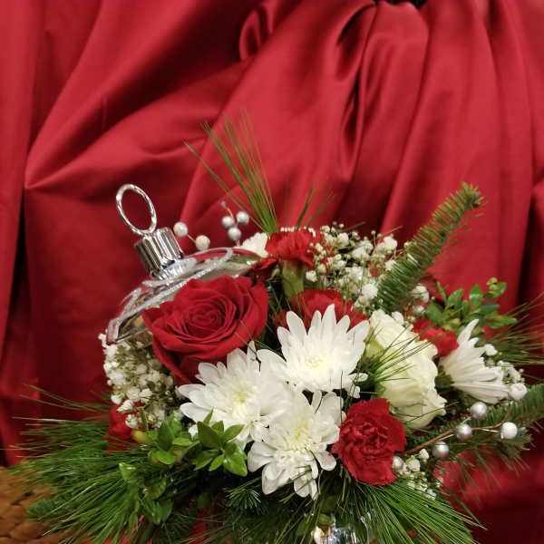Red and white floral arrangement in a clear ornament-shaped vase