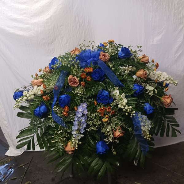 Large floral spray with blue and peach roses and ribbon accents