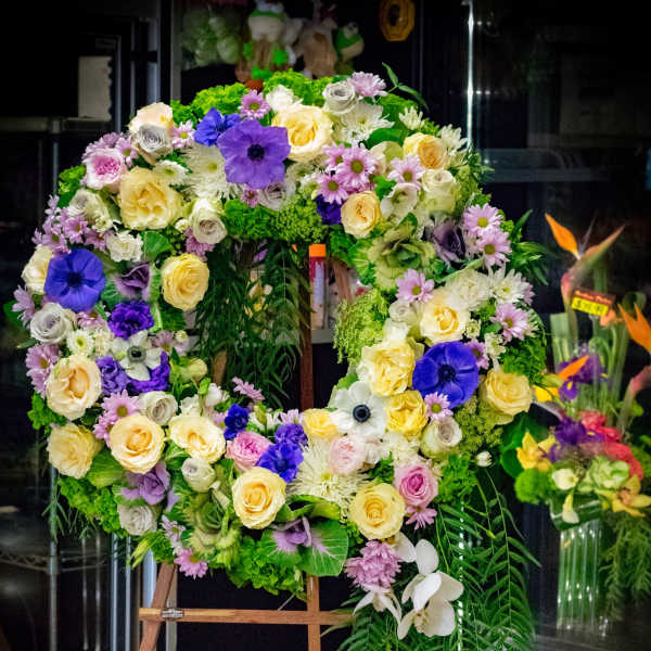 Large floral wreath on an easel with purple, yellow, white, and pink flowers