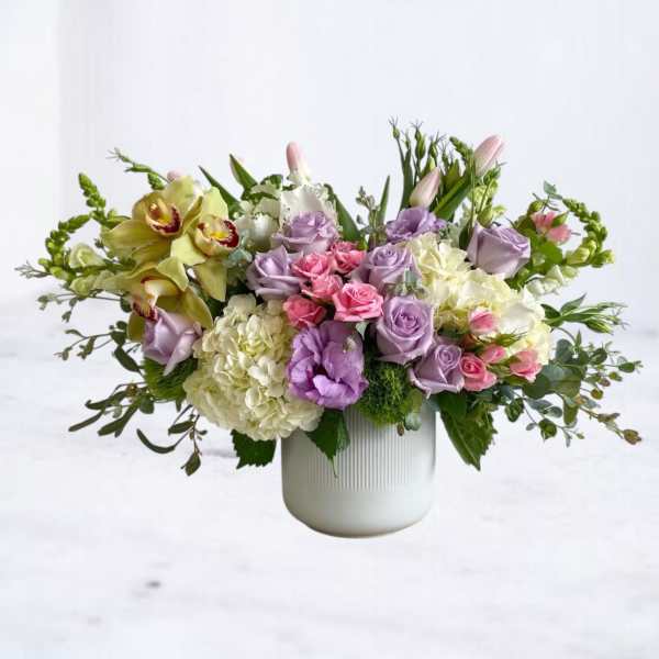 Mixed pastel bouquet in a white vase with roses, hydrangeas, and orchids