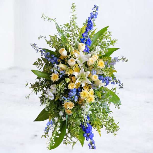Tall floral spray with white lilies, cream roses, and blue flowers