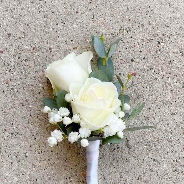 White rose boutonniere with small white filler flowers and white ribbon wrap