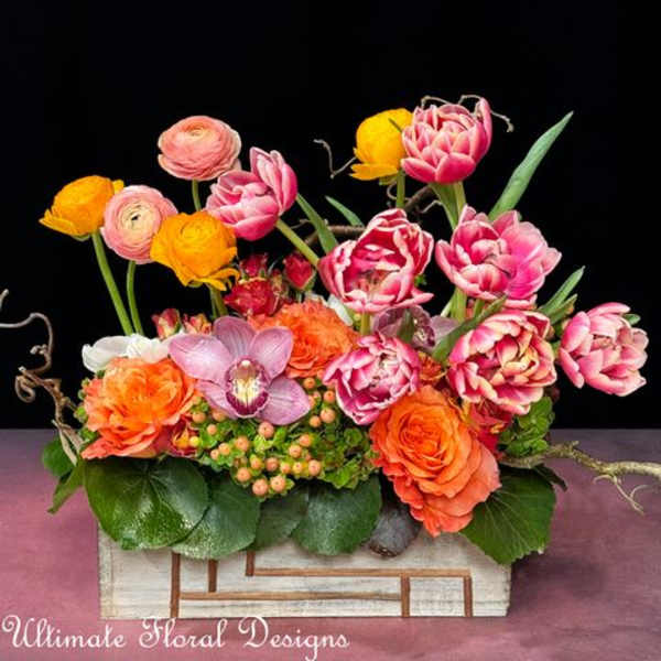 Colorful floral arrangement with pink, orange, and yellow blooms in a rectangular container