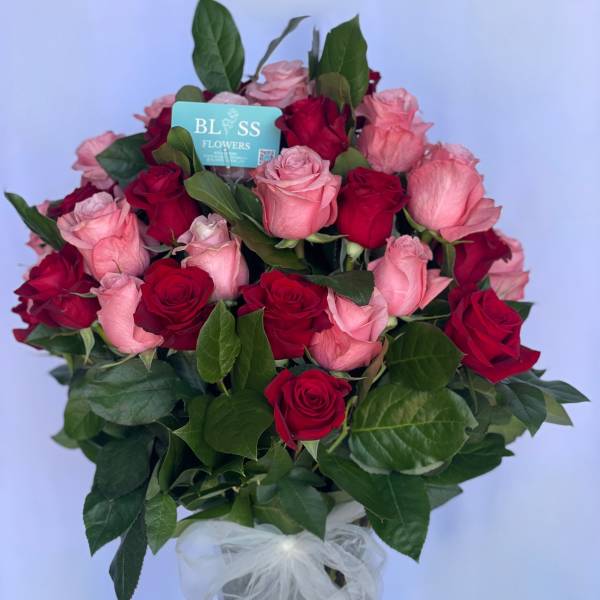 Bouquet of red and pink roses in a clear vase with a white bow