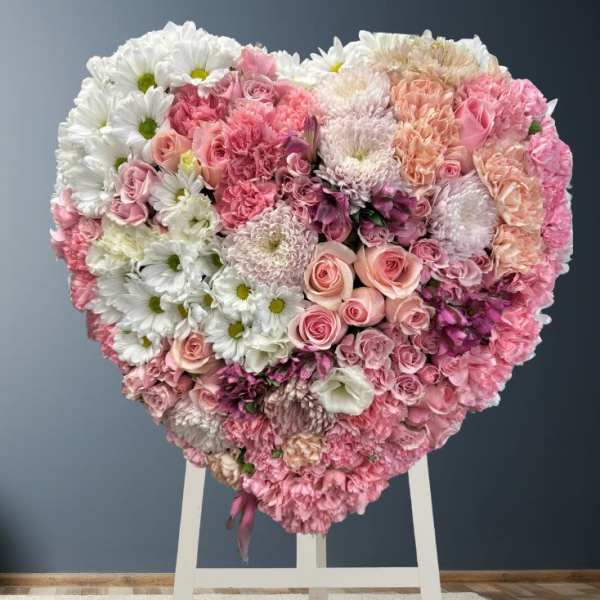 Heart-shaped floral arrangement of pink and white flowers on a stand