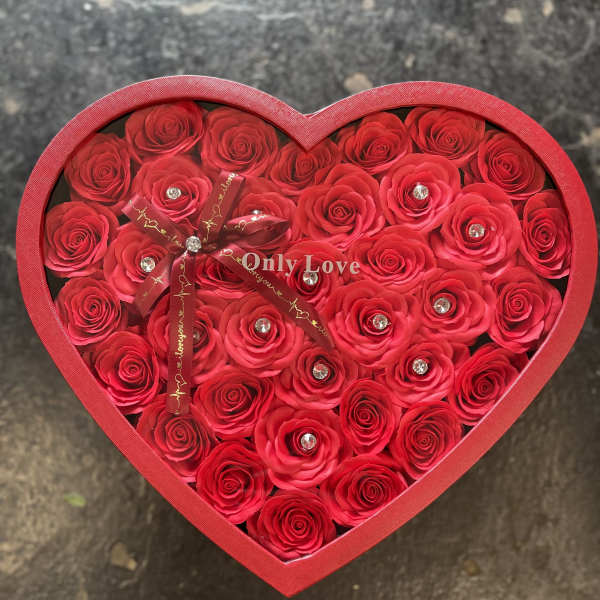 Heart-shaped box filled with red roses and a ribbon bow