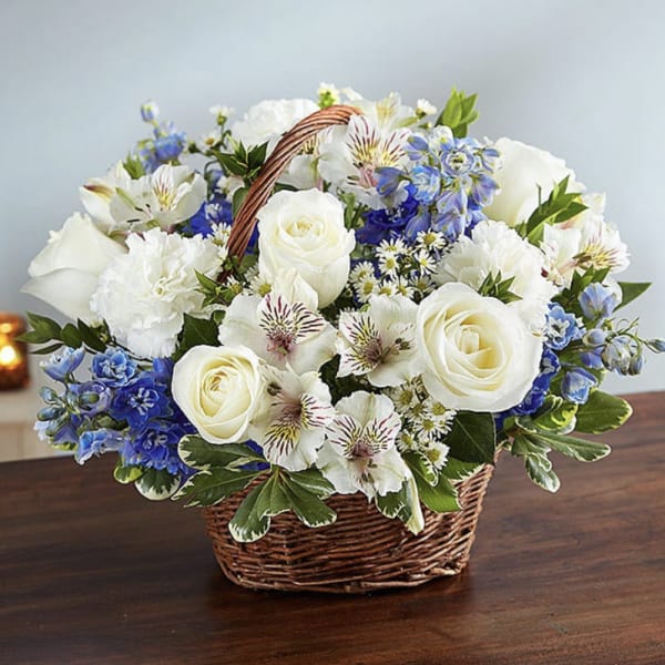 White and blue mixed flower basket arrangement on a wooden table