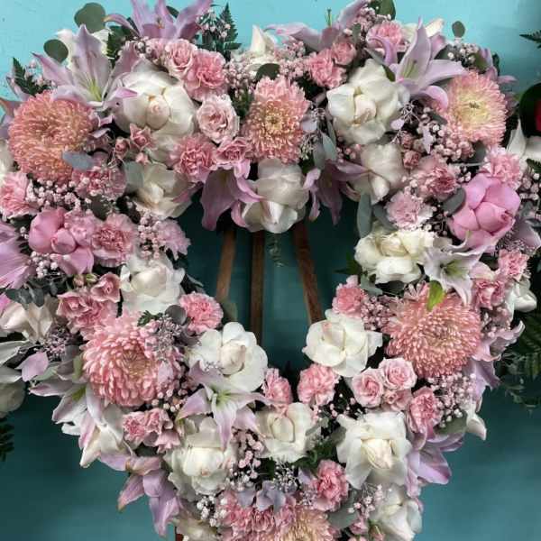 Heart-shaped floral wreath with pink and white flowers on a stand