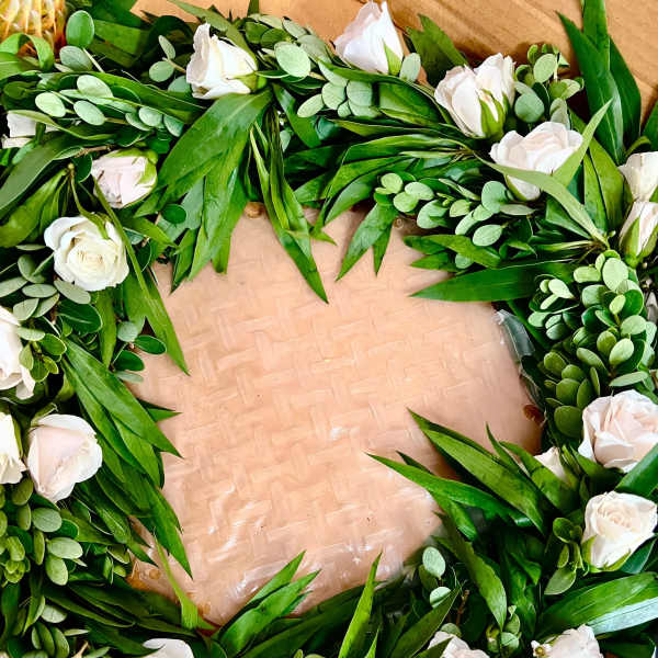 Wreath of white roses and greenery arranged in a circle on a flat base