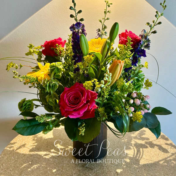 Mixed bouquet with pink roses, yellow daisies, and lilies in a vase