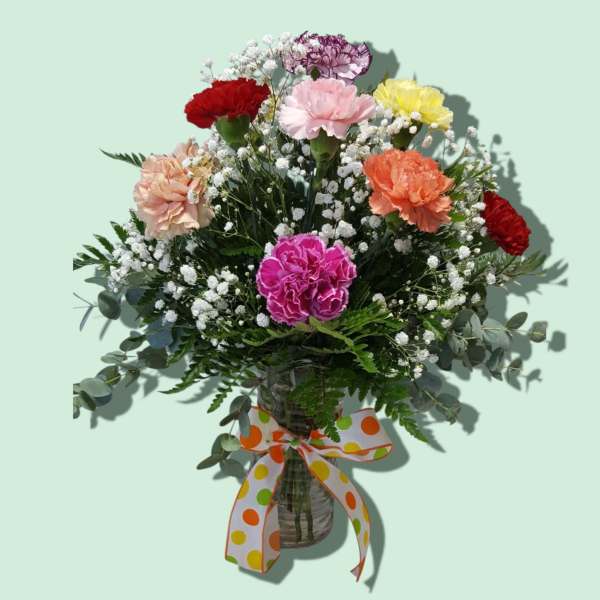 Mixed carnation bouquet in a glass vase with a polka-dot ribbon