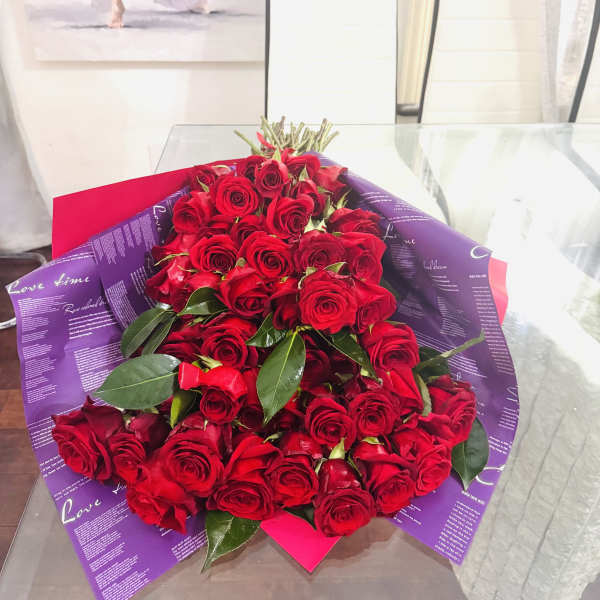 Large bouquet of red roses wrapped in purple paper