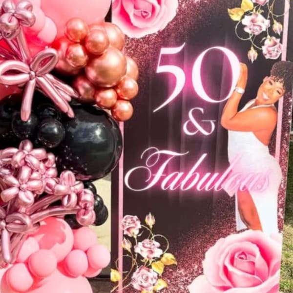 Pink and black balloon display beside a "50 & Fabulous" party sign