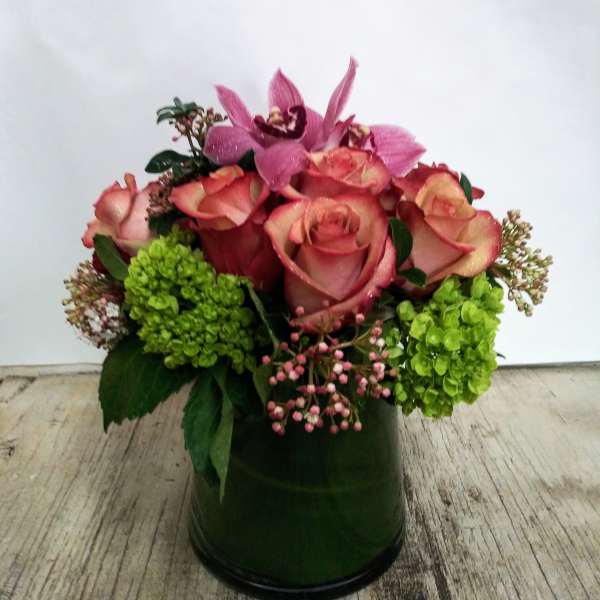 Pink roses and orchids arranged in a green vase