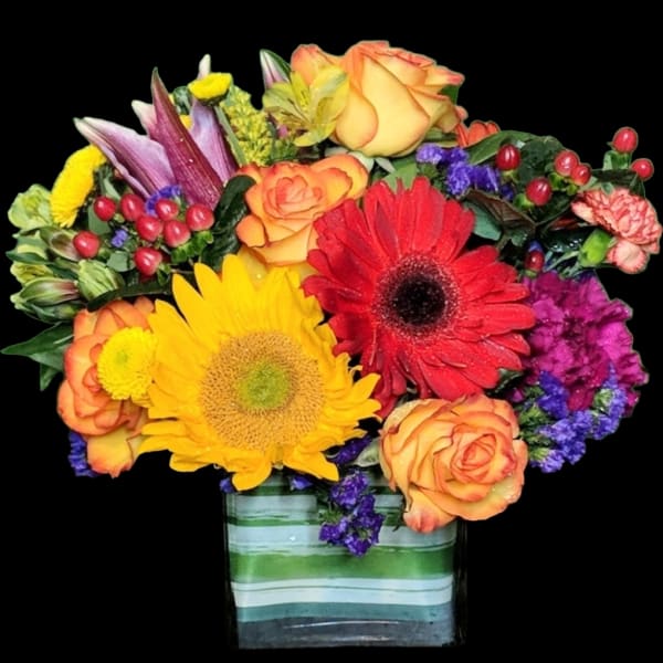 Mixed bouquet of sunflowers, roses, and gerbera daisies in a striped glass vase