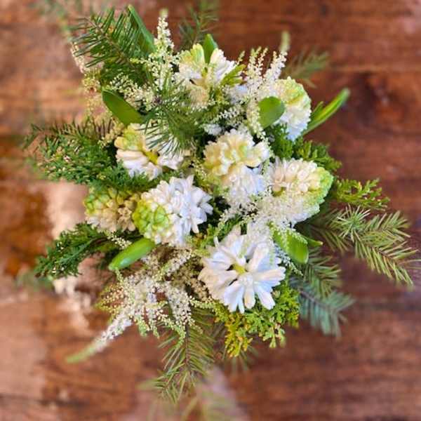 White floral bouquet with green accents and pine branches