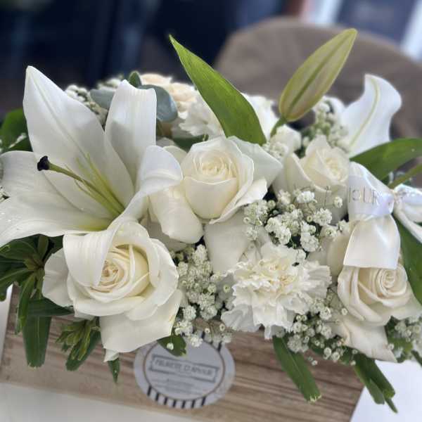 White roses and lilies arranged in a wooden box