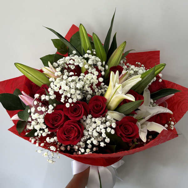 Bouquet of red roses and white lilies wrapped in red paper