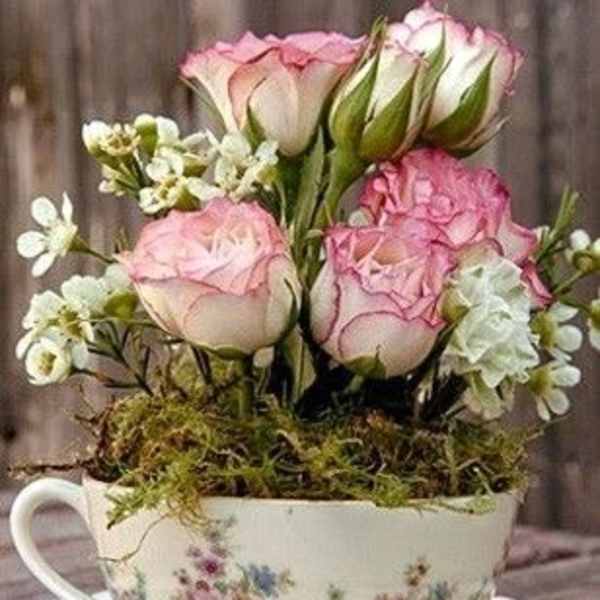 Pink roses arranged in a floral teacup with a matching saucer