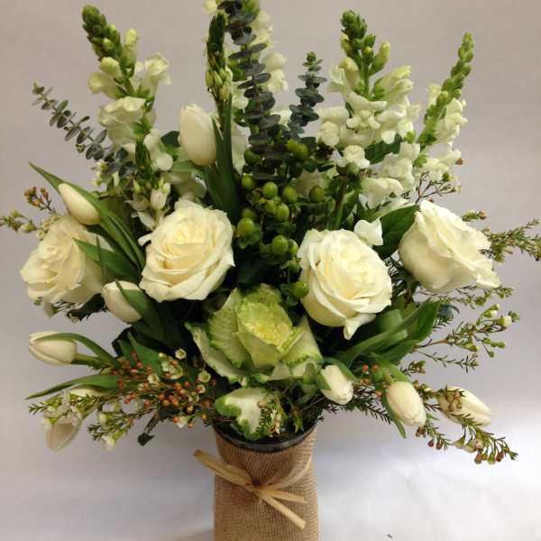 White roses and tulips arranged in a burlap-wrapped vase