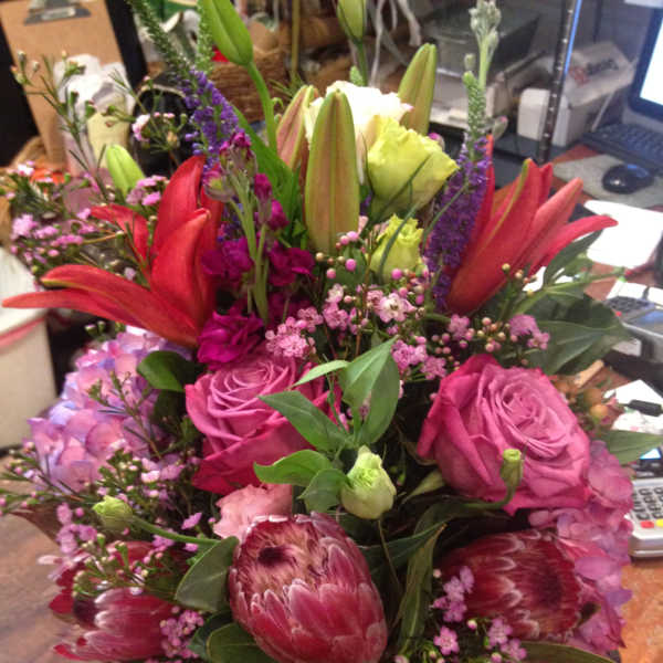 Mixed bouquet with pink roses, red lilies, and purple filler flowers