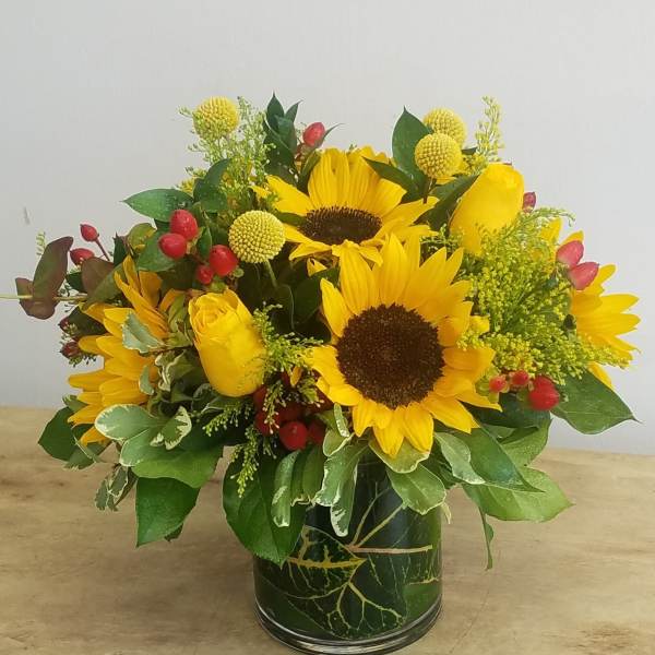 Sunflower and yellow rose arrangement in a glass vase